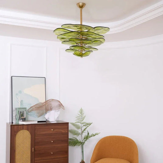 The green petal shade lit above a wooden cabinet with an orange armchair beside it