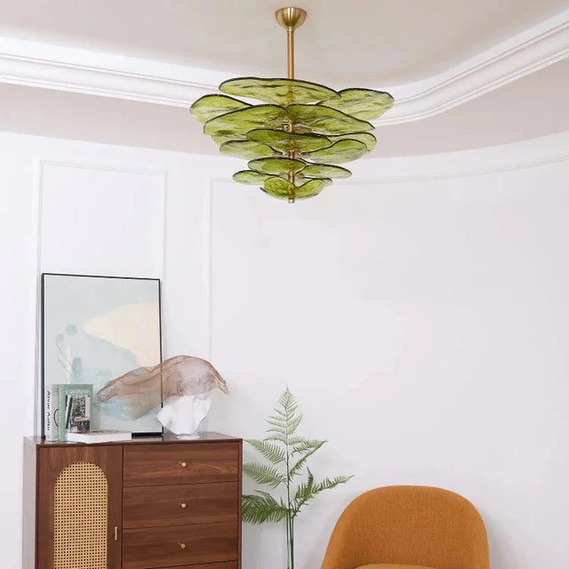 The green glass petal shade lit in a corner above a wooden chest and an armchair