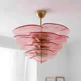 The pink glass petal shade lit under a plain white ceiling