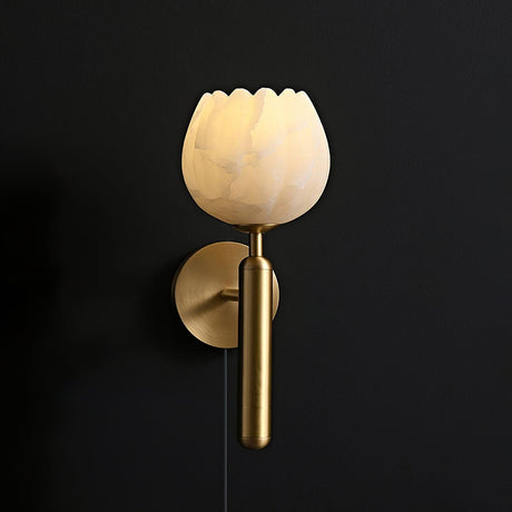The brass version lit against a dark wall, the stone flower glowing