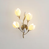 The porcelain blooms lit warm on a beige wall, the gold branches between them