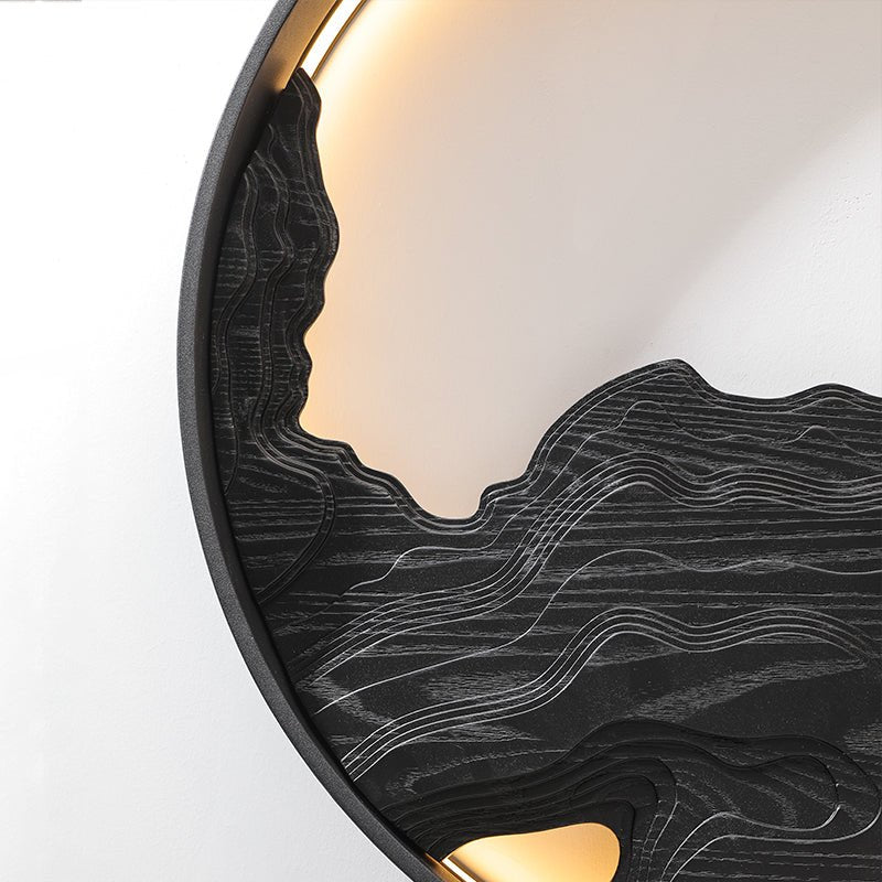Black carved disc lit along its upper edge, seen from a low angle