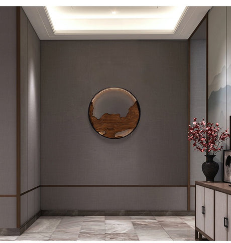 Carved disc lit on an entry wall above a run of cabinets and a vase