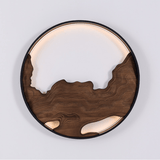 Round wall light with carved wood contours and a lit band above them