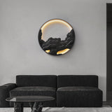 Carved disc lit on a pale wall above a dark sofa and a low table