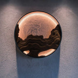 Carved disc lit on a textured plaster wall, the light spilling around it