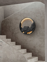 Carved disc lit on a stairwell wall beside a run of pale stone steps