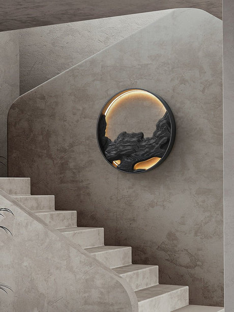 Carved disc lit on a stairwell wall beside a run of pale stone steps