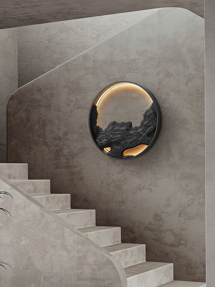 Carved disc lit on a stairwell wall beside a run of pale stone steps