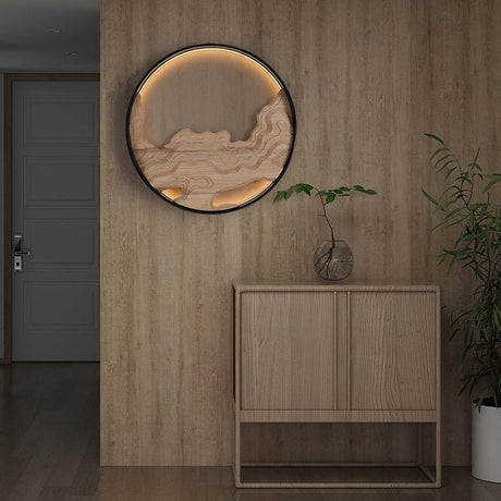 Carved disc lit on a wood paneled wall above a low cabinet and a plant