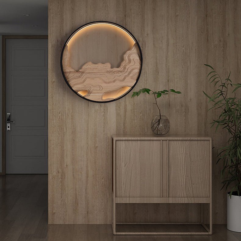 Carved disc lit on a wood paneled wall above a low cabinet and a plant