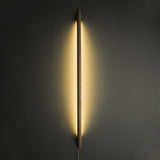 Dark rod lit vertically, the backglow washing the wall on both sides