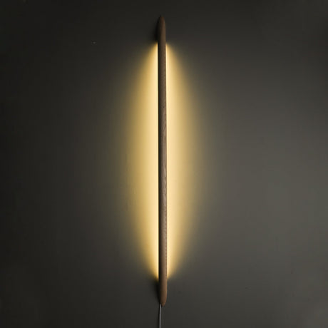 Dark rod lit vertically, the backglow washing the wall on both sides