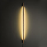 Long rod lit vertically on a dark wall, light spilling around it