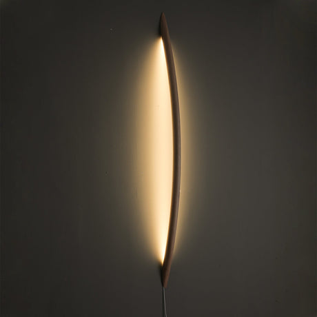 Wood rod lit, a warm halo of light tracing the wall behind it