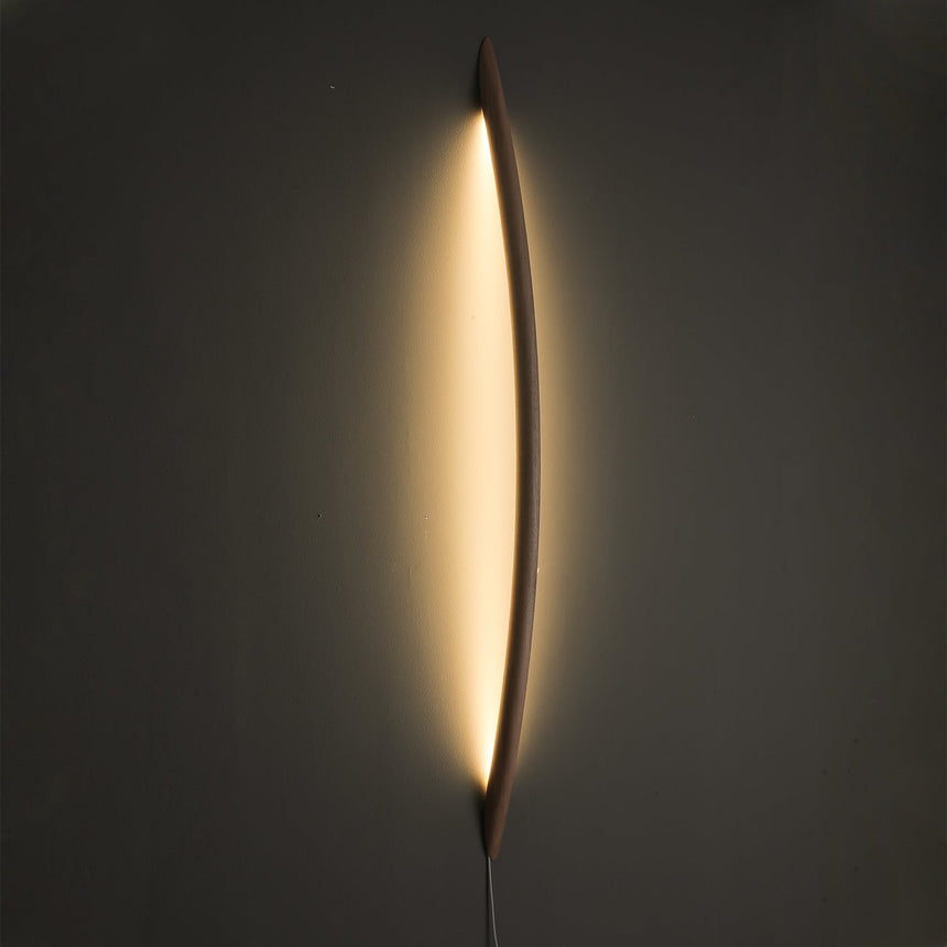 Wood rod lit, a warm halo of light tracing the wall behind it