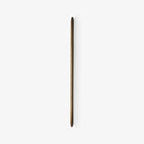 Slim tapered walnut rod mounted flat on a pale wall, seen unlit