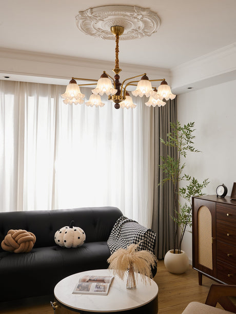 Chandelier lit above a wood chest with a mirror and a vase on it