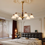 Chandelier lit in a bedroom above a bed with a leather headboard