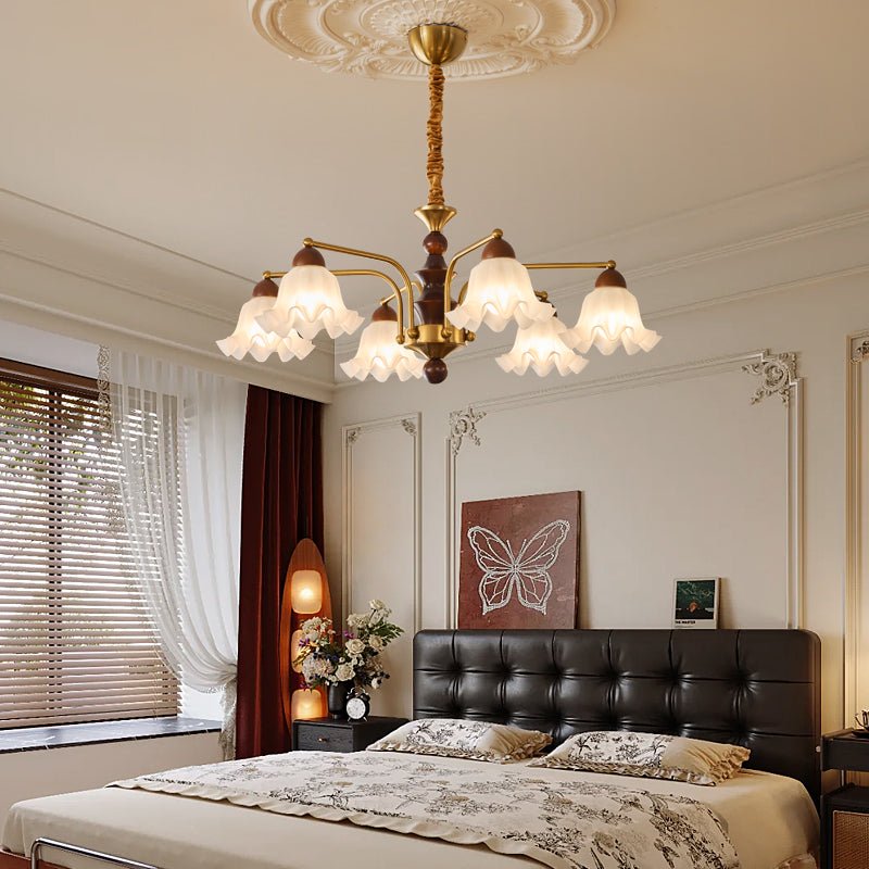 Chandelier lit in a bedroom above a bed with a leather headboard