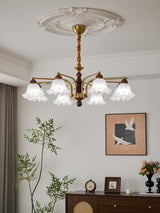 The fitting lit warm above a wood chest with a clock beside it