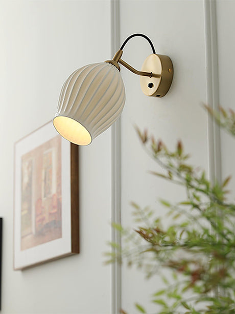 The shade glowing through its ribs beside a framed print and greenery