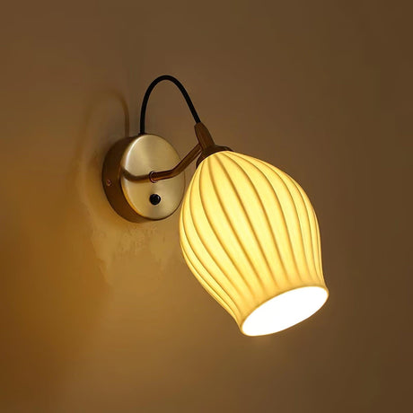 The fluted shade lit warm on a dark wall, the ribs glowing