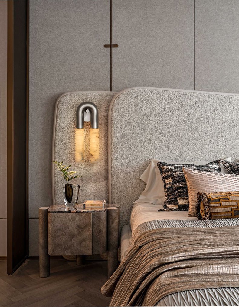 The sconce lit above a nightstand beside a bed with a woven headboard