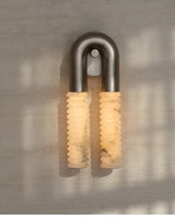 The lit sconce on a sunlit plaster wall with soft window shadows