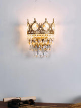 The crown lamp lit on a pale wall above a wood desk