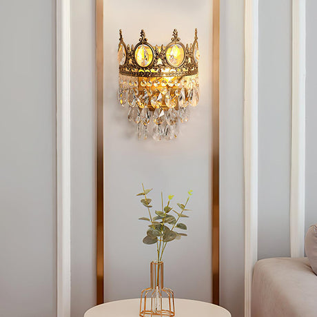 The crown lamp on a narrow wall above a small vase of greenery and a sofa arm