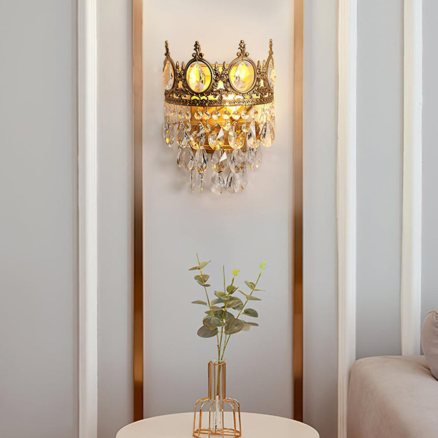 The crown lamp on a narrow wall above a small vase of greenery and a sofa arm