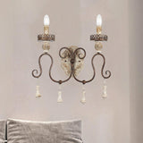 Sconce on a wall above a bed with a soft gray cushion against the headboard