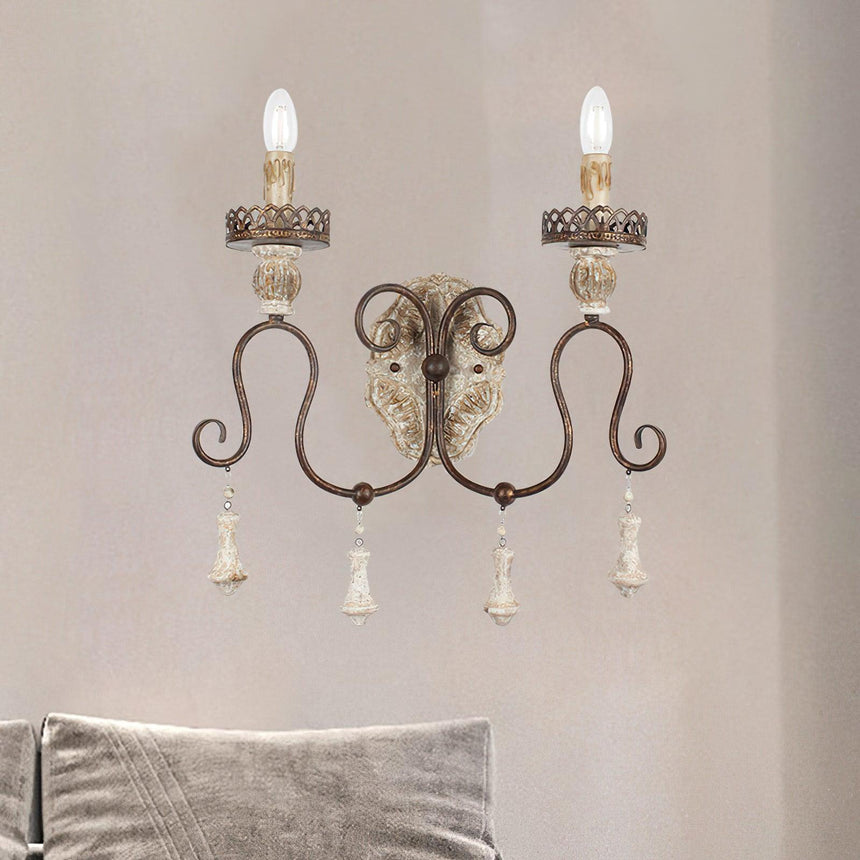 Sconce on a wall above a bed with a soft gray cushion against the headboard