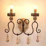Two candle lamps lit warm on the iron arms above the carved wood plate