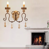 Sconce lit on a wall above a fireplace mantel with flowers and a lit fire