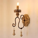 The two arm sconce lit, the carved wood plate glowing behind the flames