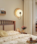 Sconce lit above a cane headboard with flowers and a curtain beside it
