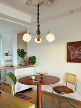 Chandelier lit above a round dining table beside a kitchen counter