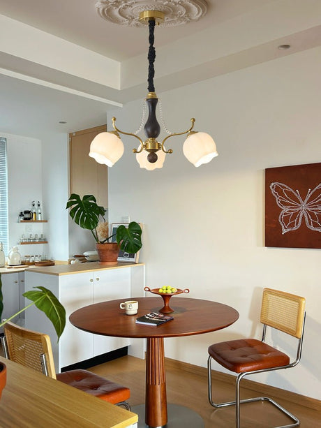 Chandelier lit above a round dining table beside a kitchen counter