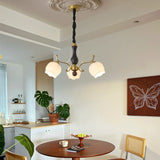 The tulips lit above a round table with a cane back chair beside it