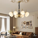 Chandelier lit above a tan sofa in a room hung with framed pictures