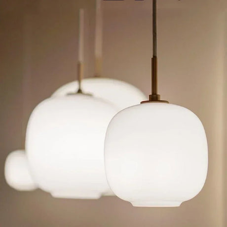 Three frosted glass globes of different sizes hung together on brass cords