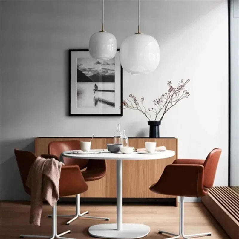 Two frosted glass globes lit above a dining table with red chairs