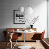 Two frosted glass globes lit above a dining table with red chairs