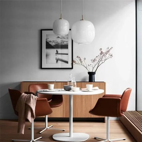 Two frosted glass globes lit above a dining table with red chairs