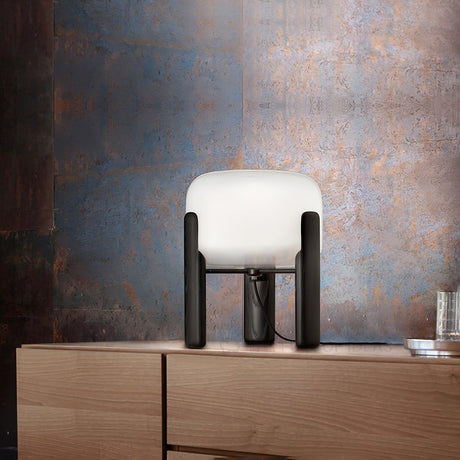 Frosted glass table lamp lit at night on a wood dresser