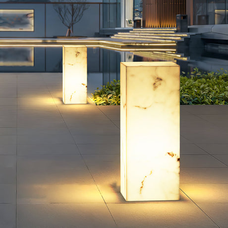 Two lit in a courtyard beside a water channel and low planting