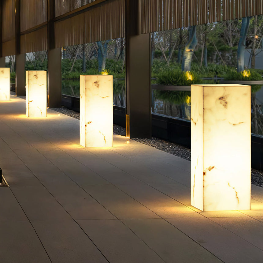 Four lit in a line along a paved walk beside a lit timber screen
