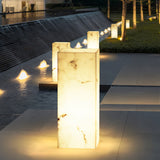 Two lit at the edge of a still water channel with paving beyond
